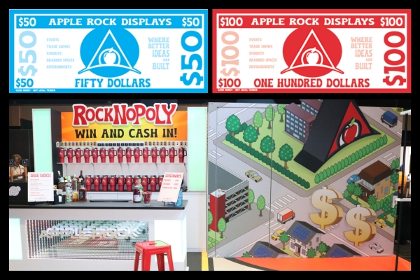 Prize table using Apple Rock’s $50 and $100 Bucks at ExhibitorLive and EMS exhibit featuring branded tumblers, squishy dollars, and giveaways for gamified challenges.